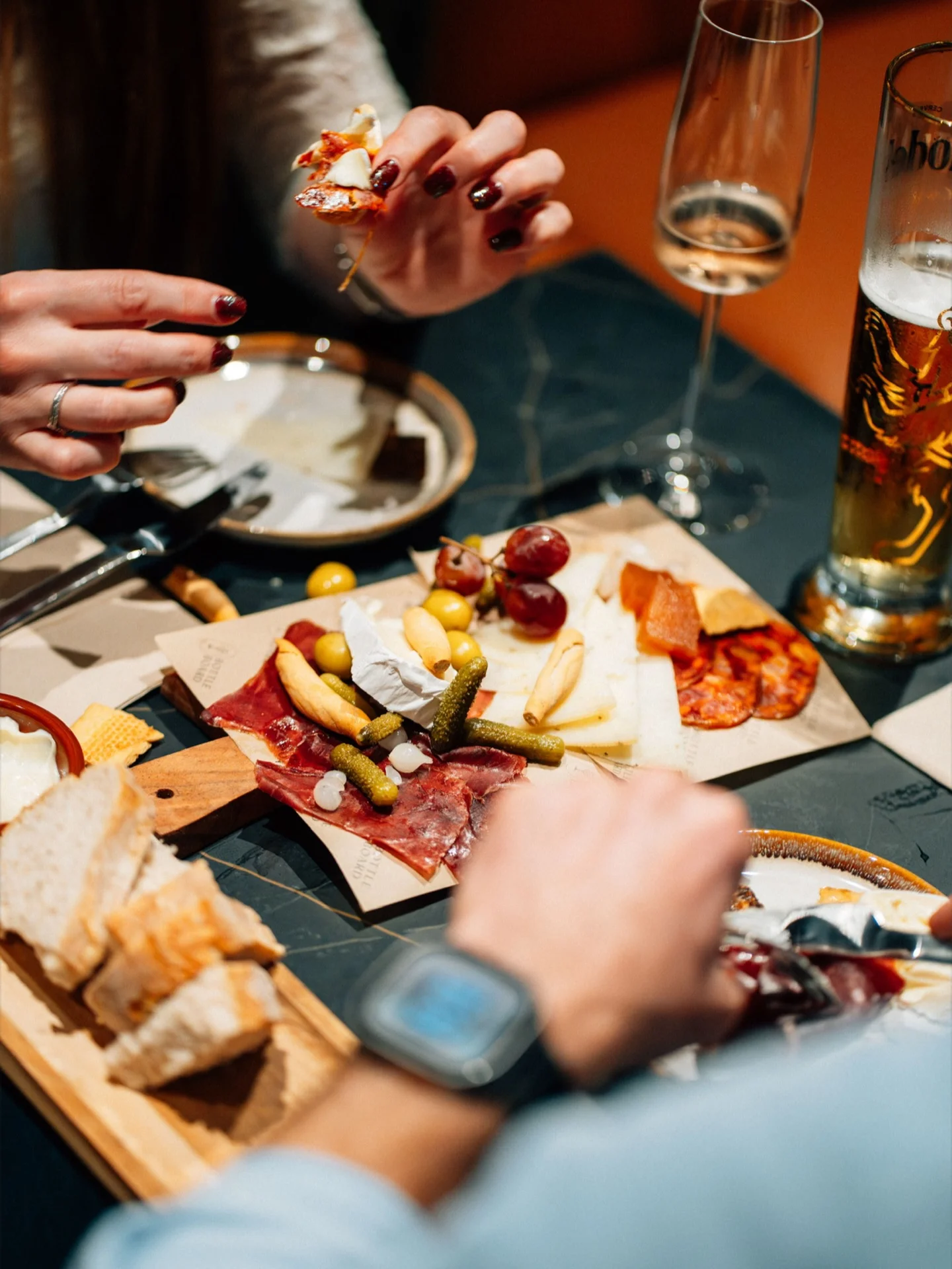 Friends sharing a charcuterie and cheese board over drinks at Bottle & Board