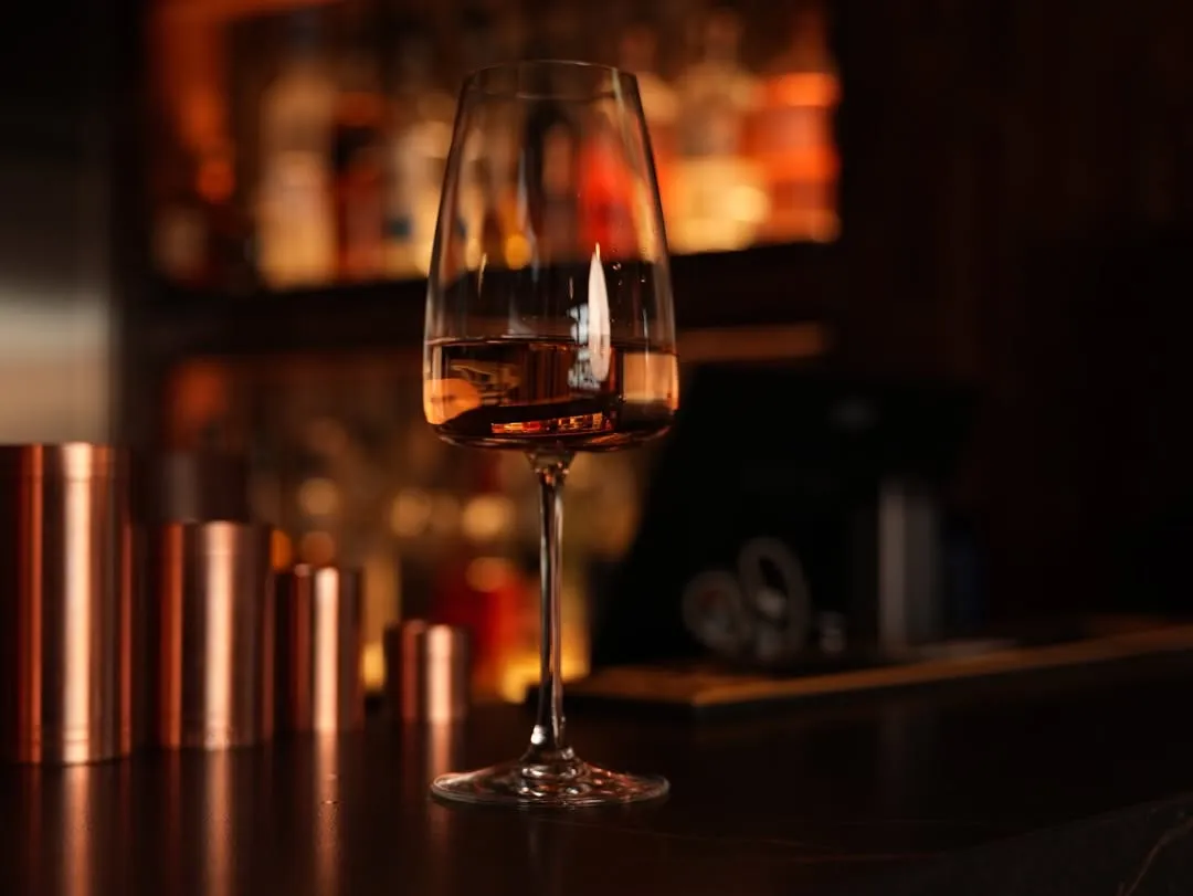 A glass of wine on the softly lit bar at Bottle & Board